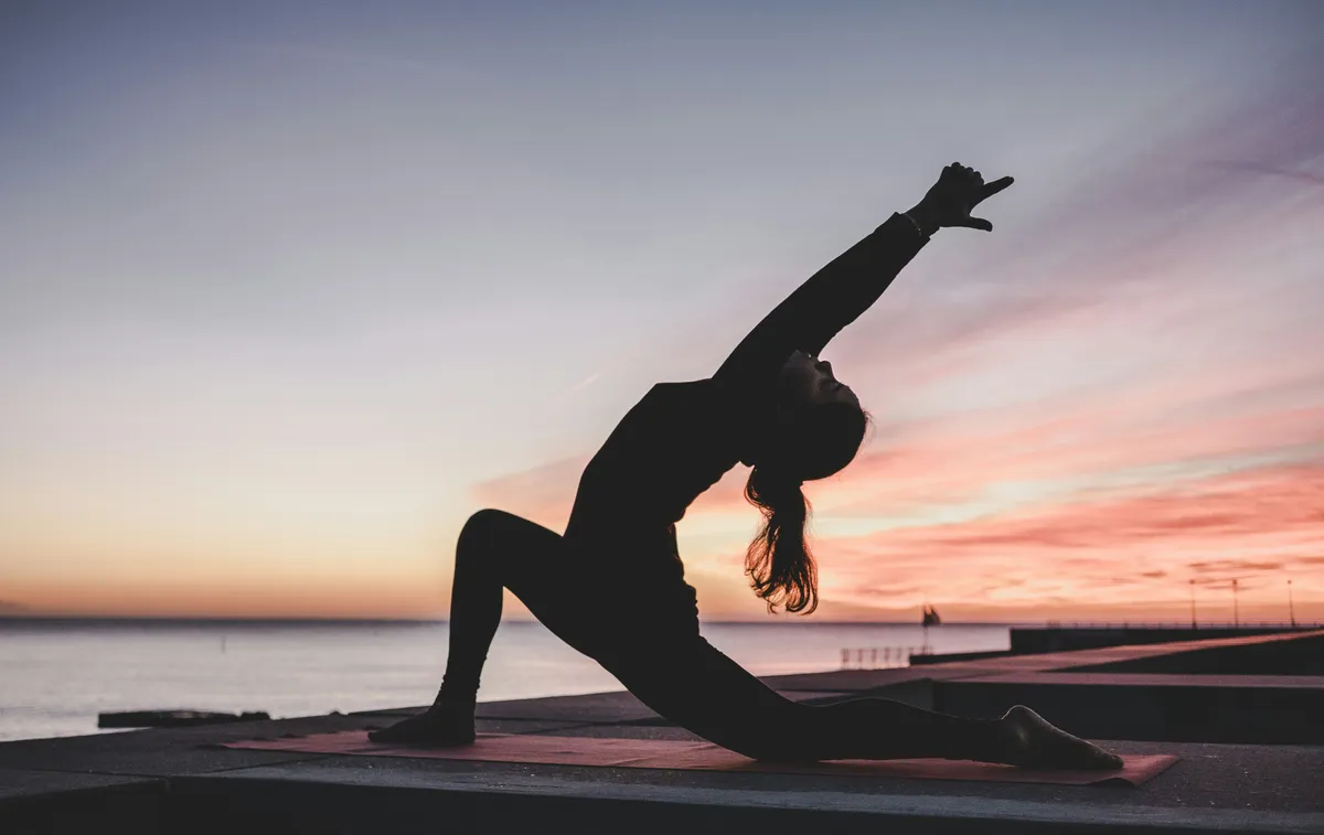 Silhouette of a person practicing yoga at sunset