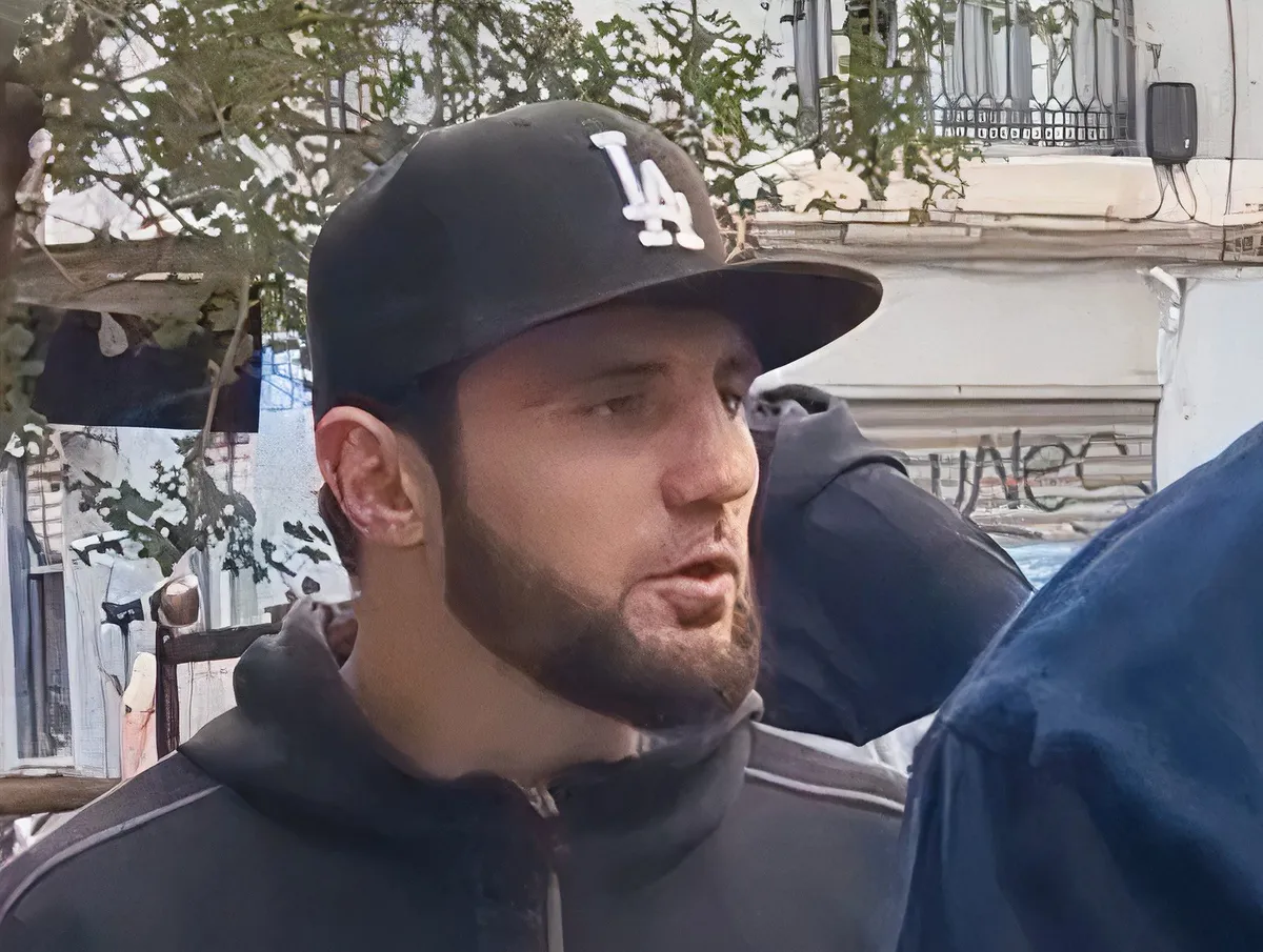Mann mit dunkler Kappe spricht auf einer Stadtstraße