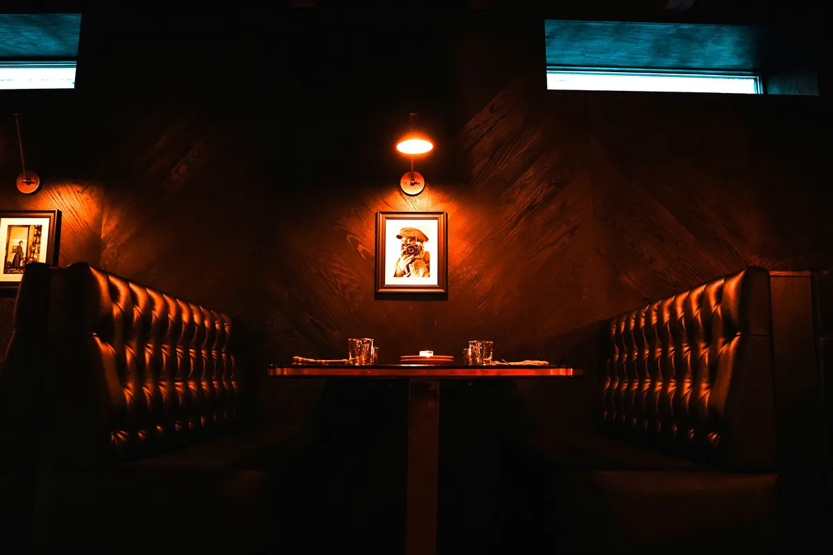 Dimly lit booth with padded seats and a small lamp